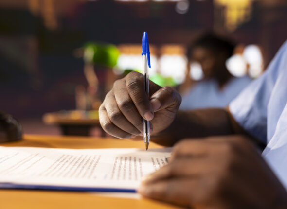 Black male pupil makes notations about practice methods to prepare for an exam
