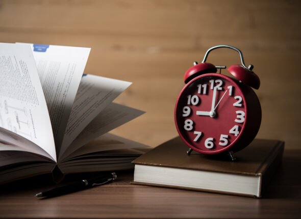 Books and alarm clock on wooden table. Education concept.